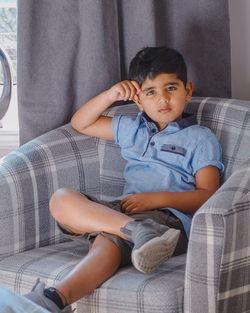 Portrait of boy sitting on sofa at home