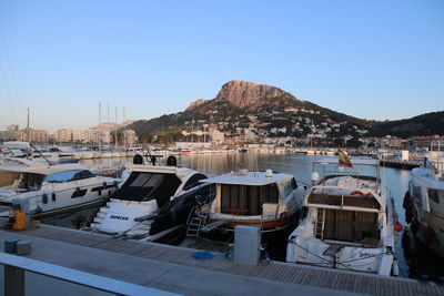 Sailboats moored in city against clear blue sky