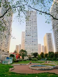 Park by buildings against sky in city