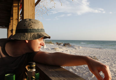 Midsection of man sitting at beach against sky