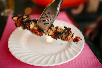 Close-up of tongs serving grilled meat on table