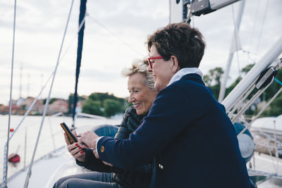 Smiling senior women using mobile phone on yacht