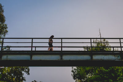 Boy on railing against clear sky