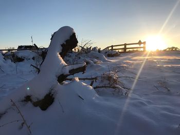 Snow on field against sky during sunset