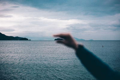 Optical illusion of hand holding island against cloudy sky