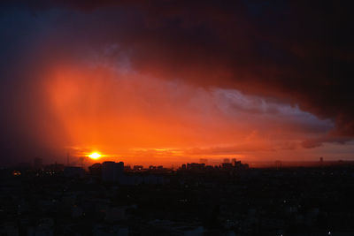 Silhouette buildings against dramatic sky during sunset