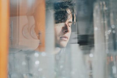 Portrait of young woman looking through glass window