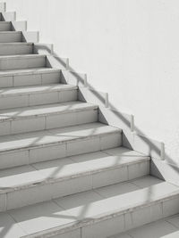 White exterior of outdoor staircase with railing. sunlight and shadow on stone steps.urban geometry.