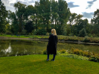 Rear view of woman standing by lake