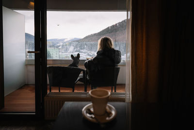 People and french bulldog dog sitting in balcony with glass window