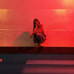 Portrait of young woman against red wall