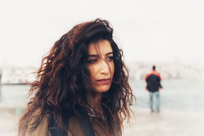 Portrait of beautiful young woman against water