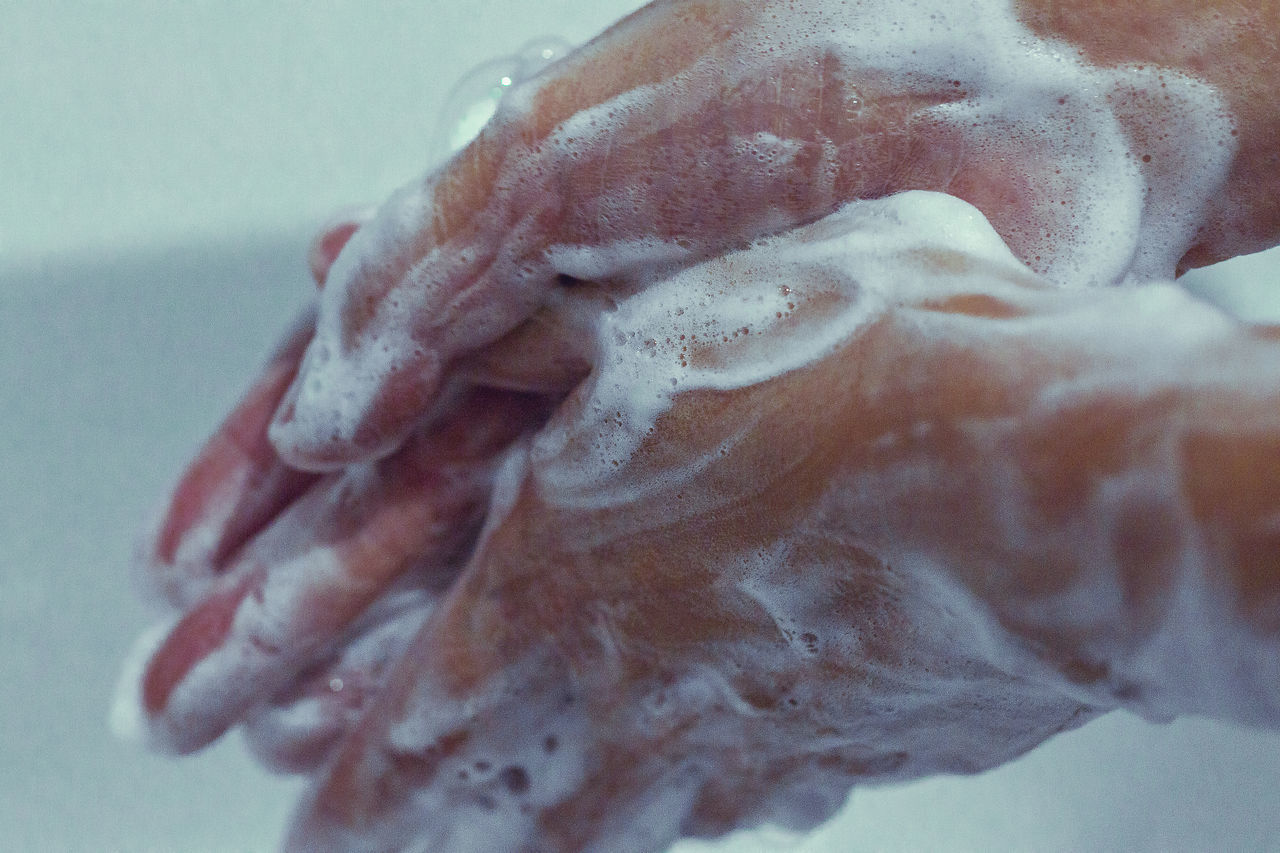 CLOSE-UP OF HUMAN HAND ON WET GLASS