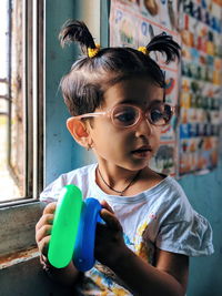 Thoughtful girl holding toys while sitting at home