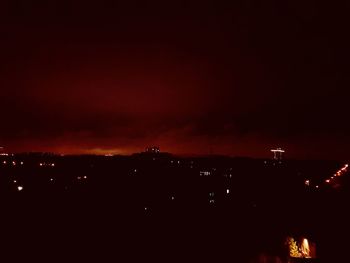 Illuminated cityscape against sky at night