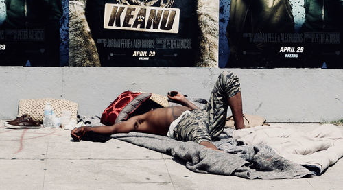 Full length of man sleeping on street in city