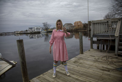 Portrait of girl standing by pink water against sky