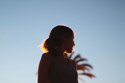 Low angle view of woman standing against clear blue sky