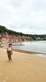 Rear view of woman with daughter at beach against sky