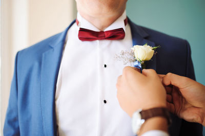 Midsection of man putting on a flower