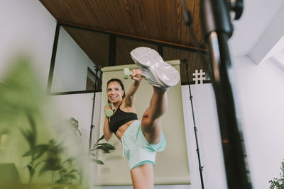 Portrait of young woman holding camera at home