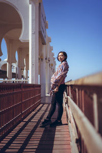 Full length of man standing on railing against sky