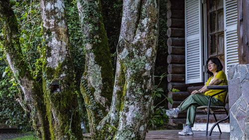 Woman sitting on chair against trees