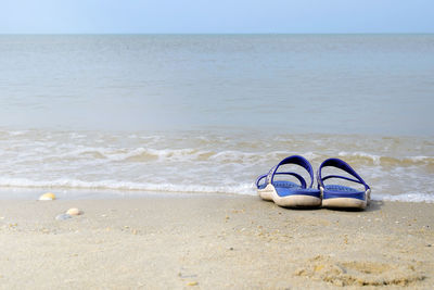 Shoes on beach against sea