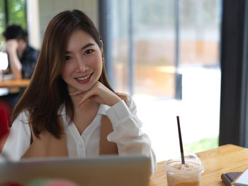 Portrait of smiling businesswoman using laptop sitting at cafe