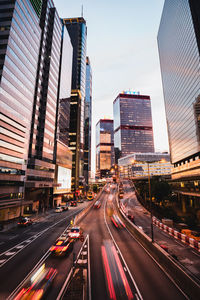 Light trails on city street amidst buildings against sky