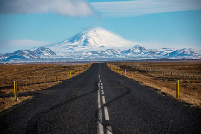 Road amidst snowcapped mountains against sky