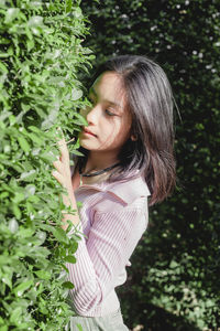 Side view of young woman standing by plants