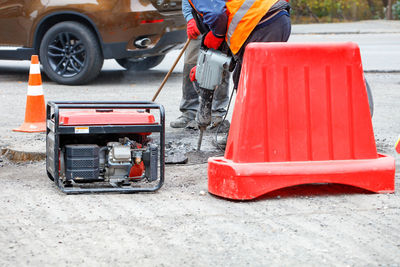 Road workers are repairing the carriageway of section of the road with an electric jackhammer fenced