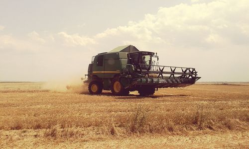 Tractor on field against cloudy sky