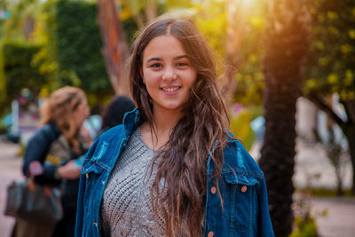 Portrait of smiling young woman standing against trees