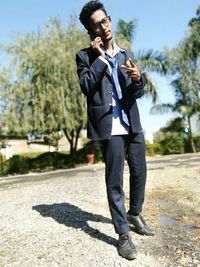 Man talking on mobile phone while gesturing against trees