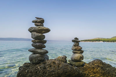 Stack of rocks by sea against clear sky