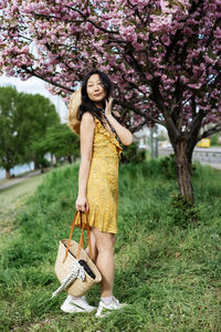 Portrait of young asian woman standing against flowers garden in spring