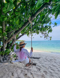 Rear view of woman sitting on beach