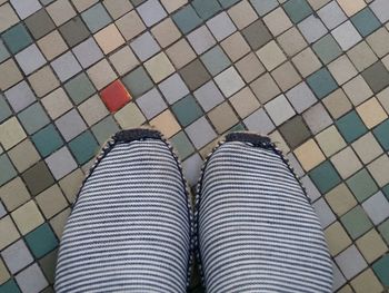 Midsection of woman wearing striped pants on tiled floor