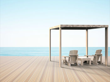 Chair on beach against clear sky
