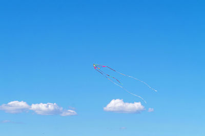 Low angle view of kites flying against blue sky