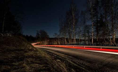 Light trails on road against sky at night