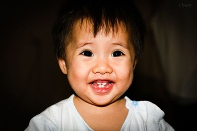 Cute cheerful baby girl looking away in dark at home