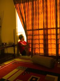 Woman looking through window at home