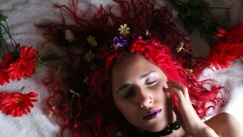 Close-up of woman lying on bed with flowers in hair 