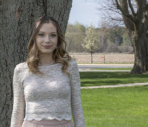 Portrait of young woman standing against trees