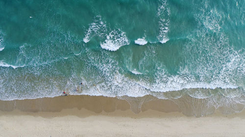 Beach on aerial drone top view with ocean waves reaching shore.