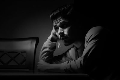 Close-up of young man using phone while sitting on table