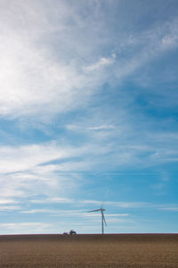 Wind turbines on field against sky